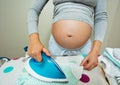 Ironing newborn baby clothes by pregnant woman Royalty Free Stock Photo