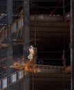 Ironworker welding on steel beams with sparks flying on a high rise