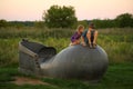 Children sitting on the giant monument of a boot on the city riverfront / promenade