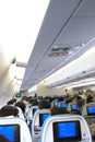 In plane cabin full of passengers during a flight viewed from the back with a view