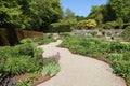 A irregular curved gravel path runs between flowerbeds of abundant perennial flowers in the formal gardens of an English country Royalty Free Stock Photo