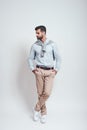 Irresistible man. Full length of charming and young man keeping hands in his pockets while standing in studio on a grey Royalty Free Stock Photo