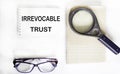 Irrevocable trust text on notepad with glasses, magnifier and notepad