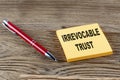 IRREVOCABLE TRUST text on sticky with pen on the wooden background