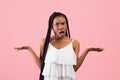 Irritated African American woman showing I DON& x27;T KNOW gesture, shrugging shoulders on pink studio background