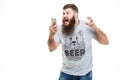 Irritated angry man with beard holding smartphone and shouting Royalty Free Stock Photo