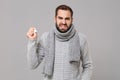 Irritated angry young man in gray sweater, scarf isolated on grey background studio portrait. Healthy lifestyle, ill Royalty Free Stock Photo