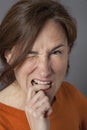 Irritated beautiful middle aged woman biting her finger, winking