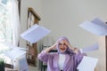 Irritated Beautiful muslim millennial businesswoman wearing a hijab sitting at office desk throwing up papers with