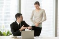 Irritated boss pointing on wristwatch while nervous employee mak