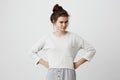 Irritated and dissatisfied brunette girl with hairbun and oval face, dark eyes, wearing loose casual sweater, frowning Royalty Free Stock Photo