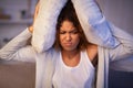 Irritated girl covering ears with pillows because of noise