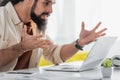 irritated hispanic freelancer gesturing near computer