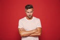 Irritated man 30s in striped t-shirt standing with arms crossed Royalty Free Stock Photo