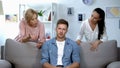 Irritated man sitting on sofa, listening wife and mother reproach, problem