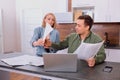 Irritated married couple sit with documents and laptop at home