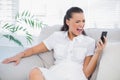 Irritated woman in white dress screaming at her smartphone Royalty Free Stock Photo