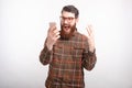 Irritated young bearded man is screaming at his mobile phone on white background Royalty Free Stock Photo