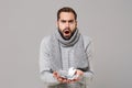 Irritated young man in gray sweater, scarf isolated on grey background. Healthy lifestyle, ill sick disease treatment