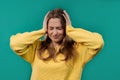 Irritated young woman with covered ears ignoring, blue background. Noise, shouts
