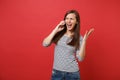 Irritated young woman screaming spreading hands talking on mobile phone, conducting conversation isolated on bright red Royalty Free Stock Photo