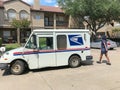 White USPS truck with woman carrier at apartment building complex in Texas, USA