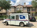 White USPS truck stops at apartment building complex on sunny da