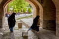 Iranian girls step over flow of water under bridge, Isfahan.