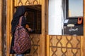 A girl in jeans and black chador with a colorful backpack changes money at an Iranian currency exchange