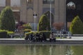 A group of young Iranians resting near a fountain in the Imam Square. Ali Qapu Palace on the background