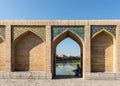 Man sitting under arch on historic Khaju Bridge (Pol-e Khajoo) on Zayanderud River in Isfahan