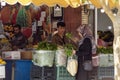 Outdoor vegetable shop. Woman buys mint and basil from a young seller