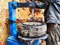 Ishim, Russia - November 27, 2023: A mechanic repairs a car wheel and makes a tire in a dirty garage. Replacement of