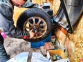 Ishim, Russia - November 27, 2023: A mechanic repairs a car wheel and makes a tire in a dirty garage. Replacement of