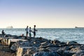 Iskenderun, Turkey - August 24, 2019: Sea fishing on spinning on the stone at seaside at sunset. Men casting lines on the