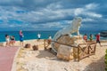 ISLA MUJERES - JANUARY 10, 2018: Outdoor view of unidentified people walking close to a stoned statue iguana in the city Royalty Free Stock Photo