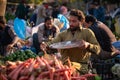 A man is weighing the vegetables with hand held scale for a