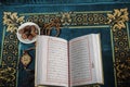 Flat lay composition of Qoran, Dates and tasbih rosary beads on top of a sajadah praying mattress