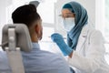 Islamic Dentist Lady In Medical Mask Checking Male Patient& x27;s Teeth In Clinic