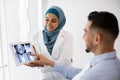 Islamic Dentist Woman Showing Teeth Xray On Digital Tablet To Male Patient