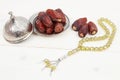 Islamic festival of Ramadan concept. with a delicious tropical dates on a silver plate and shiny rosary on a white wooden table ba Royalty Free Stock Photo