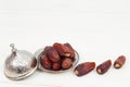 Islamic festival of Ramadan concept. with a delicious tropical dates on a silver plate and shiny rosary on a white wooden table ba Royalty Free Stock Photo