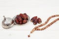 Islamic festival of Ramadan concept. with a delicious tropical dates on a silver plate and shiny rosary on a white wooden table ba