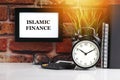ISLAMIC FINANCE text with alarm clock, books and vase on brick background Royalty Free Stock Photo