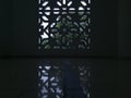 Islamic geometric patterned window casting soft light and reflections on a glossy floor inside a peaceful room. Royalty Free Stock Photo