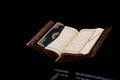 Islamic Holy Book Quran on wood carving rahle with rosary beads and prayer rug on black background. Kuran the holy book of Muslims