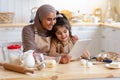 Islamic Lady Baking With Her Little Daughter In Kitchen, Using Digital Tablet