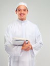 Islamic man, smile portrait and books for learning standing in white background for Arabic culture. Young person, smile