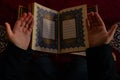 Islamic or Ramadan photo. Praying with hands and the Holy Quran in a mosque