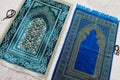 Islamic symbols, blue and green prayer rugs on a carpet in a house
